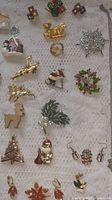 Selection of brooches, pins, earrings with Christmas motifs laid on lace cloth