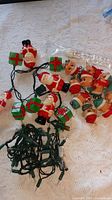 Overview of both light sets showing elf heads and Santa/gift string on green wire