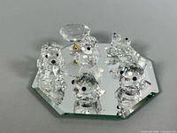 Group view of six crystal figurines arranged on octagonal mirror base