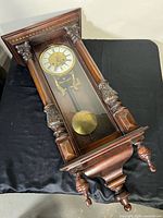 Full view of wall clock showing case, dial, pendulum