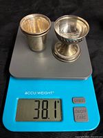 Two silver shot glasses on scale reading 38.1 g