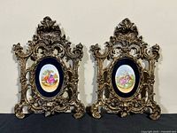 Front view of both ornate brass frames with porcelain plaques
