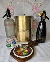Group shot showing ice bucket, two soda syphons, cheese board with knife and three shot glasses