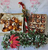 Full lot: two boxes of orange mercury glass ornaments, candy cane pick, holly sprays, poinsettia