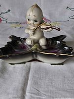 Front view of porcelain butterfly dish with Kewpie violin figurine
