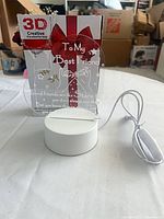 Lamp set showing acrylic plaque seated in white LED base, USB cable and retail box