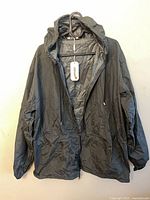 Front view of Coofandy dark gray hooded rain jacket on hanger showing zipper, hood, pockets, drawstring hem, new tag attached