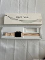 Watch in open box showing square face and pink strap