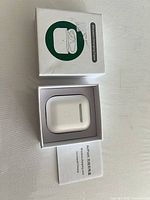 Open box showing charging case seated inside packaging with manual