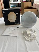 Front view of alarm clock with box, cable, adapter and manual