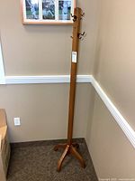 Full view of standing wood coat rack in corner