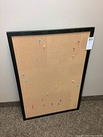 Front view of framed cork board with push pins