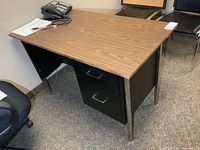 Oblique view showing entire desk, wood-grain top, metal legs, two drawers