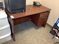 Front angled view of desk showing drawers and modesty panel
