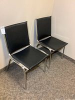 Two of the three black vinyl chrome stackable chairs side by side