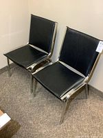 Front view of both black chrome office chairs showing upholstery and frames