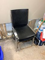 Three stacked black vinyl chairs with chrome frames