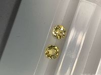 Two yellow round sapphires on white holder, overhead view