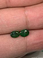 Both emeralds on fingertip showing size and colour