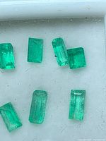 Close-up view of six emerald baguettes showing color and facet patterns