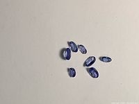 Group of seven oval tanzanite gemstones on neutral background