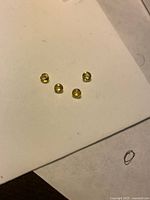 Four loose yellow round gemstones on white background