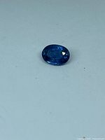Oval blue sapphire against white background showing overall shape and colour