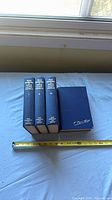 Spines and covers of all four volumes beside measuring tape