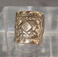 Front view of silver ring showing raised figural scene and border