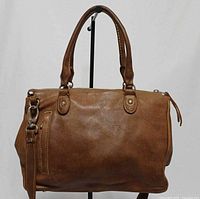 Front view of brown leather Roots satchel showing handles, detachable strap, zip top, hardware