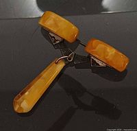Front view of brooch showing amber cabochons, silver bar and pendant
