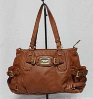 Front view of brown leather Michael Kors Gansevoort handbag showing logo plate and buckle details