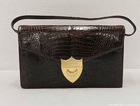 Front view of Paloma Picasso evening bag showing crocodile-embossed leather and gold-tone shield clasp