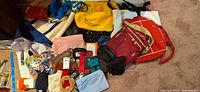 Wide view of mixed bags, wallets, gloves, shoelaces and accessories spread on carpet
