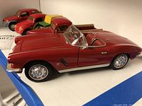 Side view of red Corvette convertible, red pickup, green tractor, red SUV visible