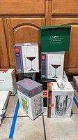Stacked boxed RCR wine glasses, pitcher, mug, and green box