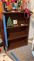 front view of brown three-shelf bookcase with items on top and inside