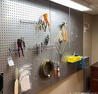 Overall pegboard with tools, wire coil, organizer box, stained glass panel