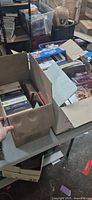 Two open cardboard boxes filled with boxed CD sets and jewel-case CDs