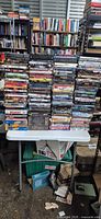 Front view showing seven tall stacks of DVDs on small folding table