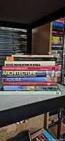 Full stack of nine architecture and design books on shelf