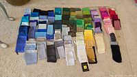 Full assortment of pocket squares and small scarves laid out by color groups on carpet