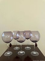 Front view of five purple-tinted goblets on table