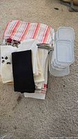 stack of folded kitchen towels, napkins, oven mitts beside nested Glasslock containers