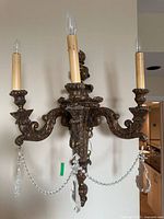 Front view of one sconce showing three arms, candle sockets, crystals