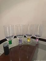 Four clear goblets showing colored stems and etched bowls