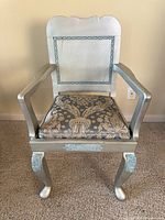 Front view of armchair showing painted frame, carved back panel, upholstered seat