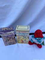 Front view of both boxed book sets and Smurfs plush toy