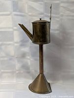 Full view of brass watering can on pedestal stand