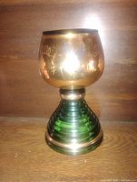 Full view of musical wine glass showing gold overlay bowl and green glass base